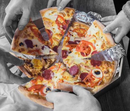 Black and white top view of hands taking pizza. Concept of friendship at work, unity,  teamwork, partnership.の写真素材