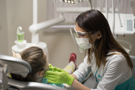 Female Dentist checking little girl patient at dental clinic.の写真素材