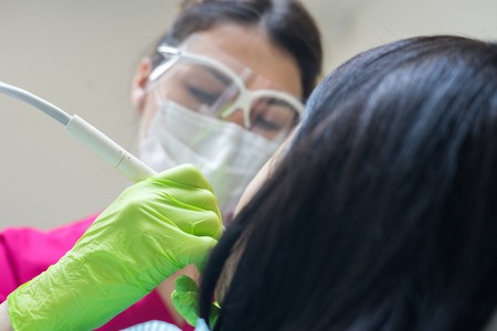 Female dentist cleaning teeth of patientの写真素材
