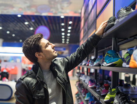 young male customer choosing sneakersの写真素材
