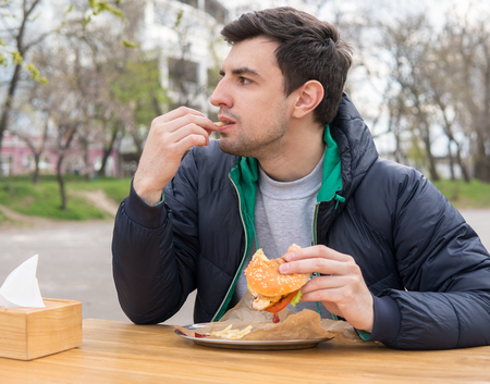 man is eating French fries in a snack barの写真素材