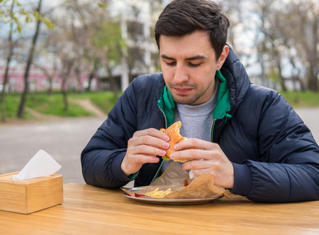 man eating a burger in street food cafeの写真素材