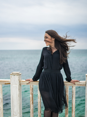 brunette girl in a black dress posing on the pierの写真素材
