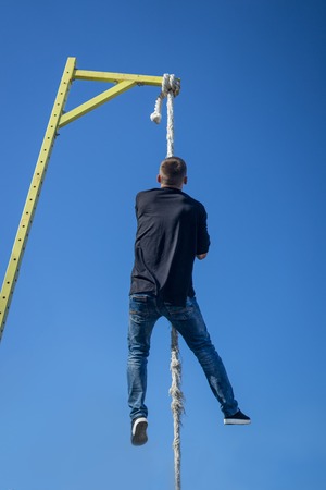 Young Athlete climbing up the Fitness ropeの写真素材