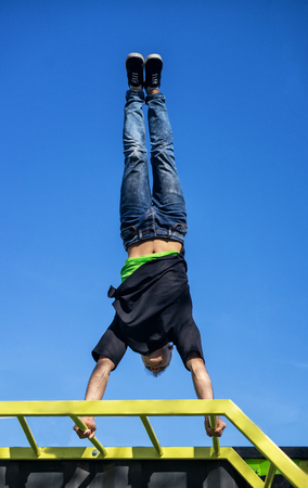 Young Athlete doing a Hand Stand On Parallel Bars In An Outdoor Gymの写真素材