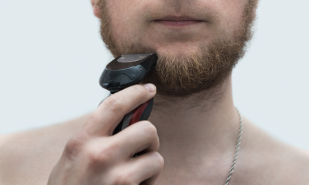 young man shaving his beardの写真素材