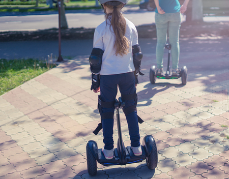 Young mother and daughter riding electric mini hoverboard in parkの写真素材