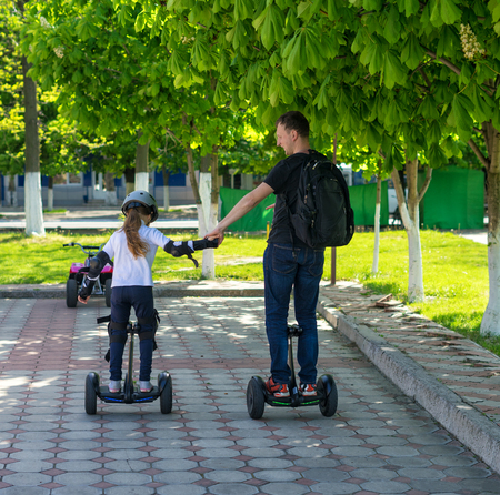Young father and daughter riding electric mini hoverboard in parkの写真素材