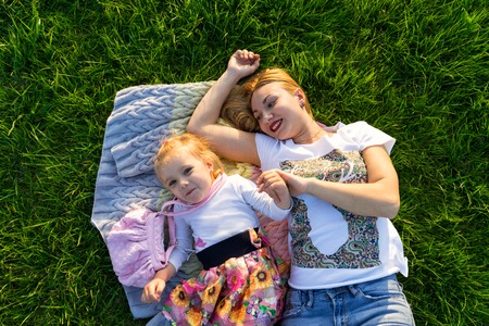 mother and her small daughter lying on green lawnの写真素材