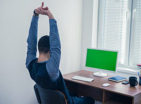 office worker sitting at computer with Chromakey on monitorの写真素材
