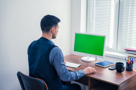 office worker sitting at computer with Chromakey on monitorの写真素材