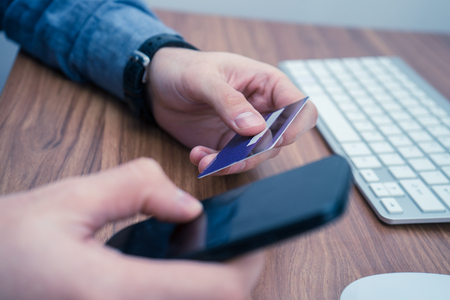 hands holding credit card and a typing on the phone making online purchaseの写真素材