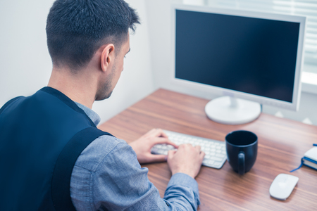 office man typing on keyboard, looking at screenの写真素材