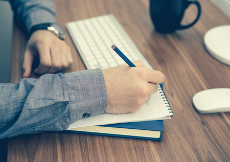 hand writing in notebook on wooden table