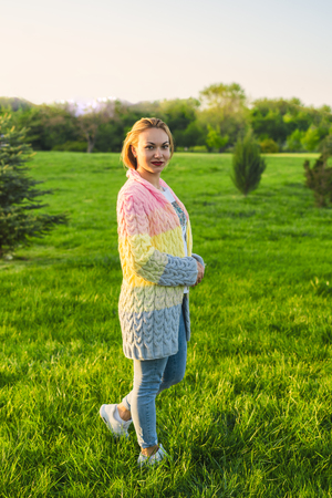 Pretty woman stands on the green grass lawn in the parkの写真素材