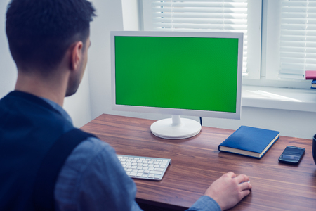 office worker sitting at computer with Chromakey on monitorの写真素材