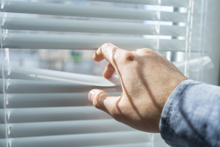 Mans hand opens the blinds or jalousie in sunny day.の写真素材