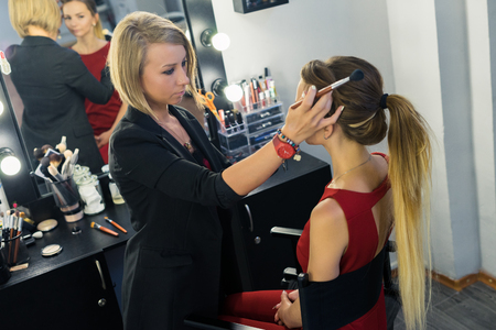 Make-up artist preparing for doing makeup to beautiful young girlの写真素材