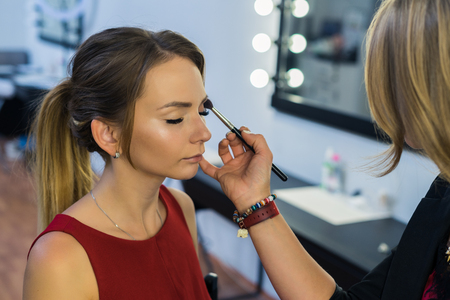 Make-up artist doing makeup to beautiful young girlの写真素材