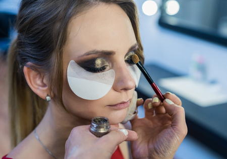 Make-up artist doing smoky eyes makeup to beautiful young girlの写真素材