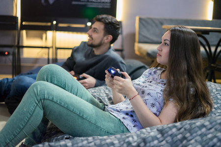 happy couple friends playing video games with joystick sitting on Bean bag chairの写真素材