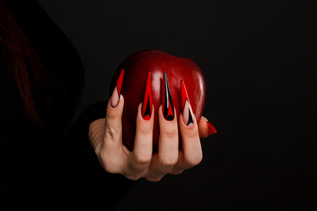 Hands with scary nails manicure holding poisoned red appleの写真素材