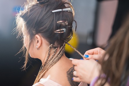 A hair stylist braids a young and beautiful girl. Zizi cornrowsの写真素材