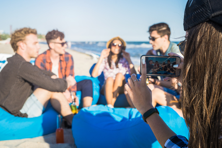 Closeup view of Girl takes a photo of group of friends on the beachの写真素材