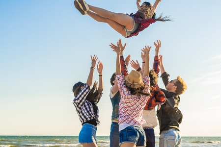 Group of hipster young friends running along beach togetherの写真素材