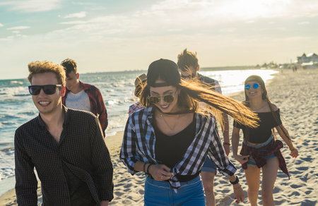 Group of young friends walking on the beach together. frienship concept. Sunset timeの写真素材