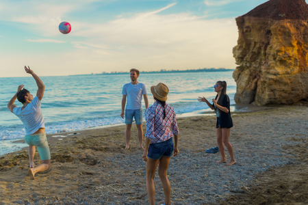 friends playing volleyball on a wild beach during sunsetの写真素材