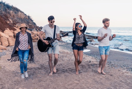 group of young and cheerful friends walking on beachの写真素材