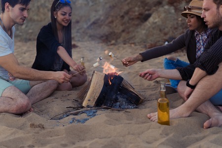 Friends on a wild beach lit a bonfire and fry marshmallowsの写真素材