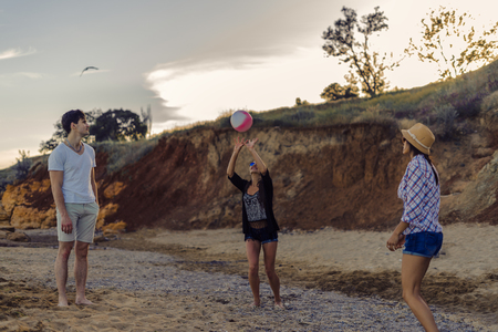 friends playing volleyball on a wild beach during sunsetの写真素材