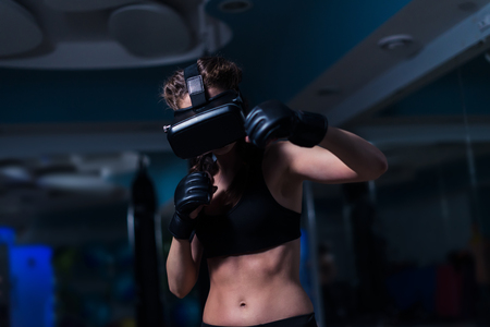 Young fighter boxer fit girl in VR glasses wearing boxing glovesの写真素材