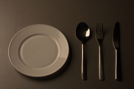Empty plate with spoon, knife and fork. low key minimalistic pictureの写真素材