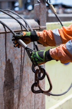 Able seaman is connecting sling. Crane loading operations on decの写真素材