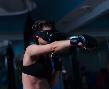 Young fighter boxer fit girl in VR glasses wearing boxing glovesの写真素材