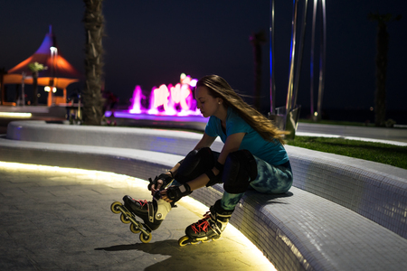 caucasian girl enjoys roller skating at night city with lights in bokehの写真素材