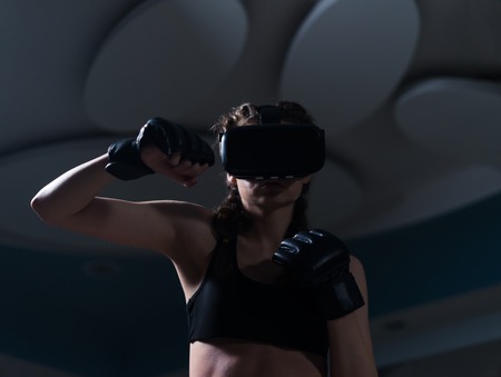 Young fighter boxer fit girl in VR glasses wearing boxing glovesの写真素材