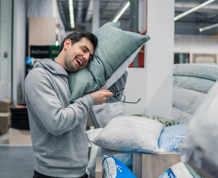 Customer man chooses pillow and linen in the supermarketの写真素材