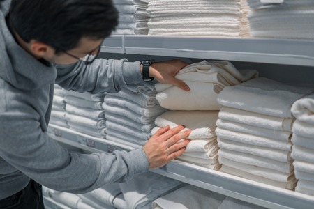 Male Customer inspecting and buying towels in supermarketの写真素材