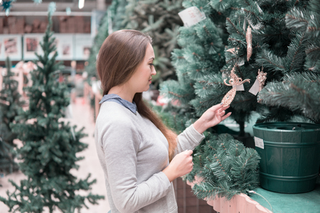 happy customer girl choosing Christmas tree for the new yearの写真素材