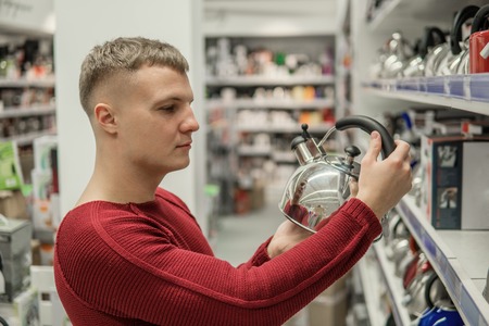 customer chooses a kettle in supermarket mall, difficult decision.の写真素材