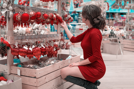 customer girl choosing decoration balls for Christmas treeの写真素材