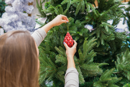 Cheerful happy customer girl choosing Christmas tree decoration ballsの写真素材