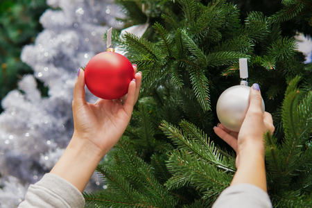 Cheerful happy customer girl choosing Christmas tree decoration ballsの写真素材