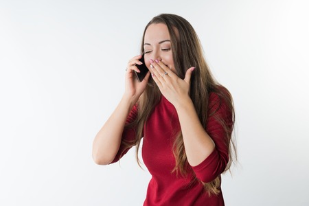 woman is speaking on her mobile phone and laughing covering her mouth with handの写真素材
