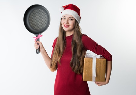 woman wearing red santa claus hat with gift frying panの写真素材