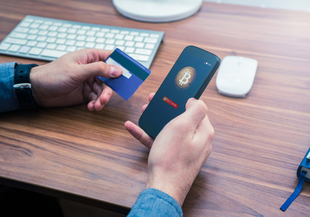 hands holding credit card and phone. bitcoin online purchaseの写真素材